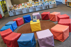 Kinder sitzen im Kreis um eine Frau und blicken interessiert auf das Buch, das sie zeigt