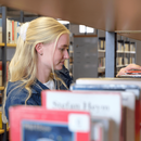Person sucht Buch am Regal aus